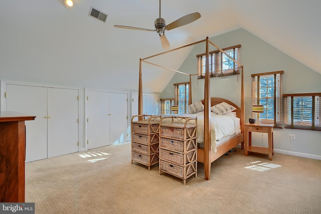 carpeted bedroom with visible vents, multiple closets, baseboards, and vaulted ceiling