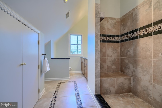 bathroom with vanity, baseboards, visible vents, a tile shower, and toilet