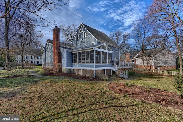 back of property with stairway, a lawn, a chimney, and a sunroom