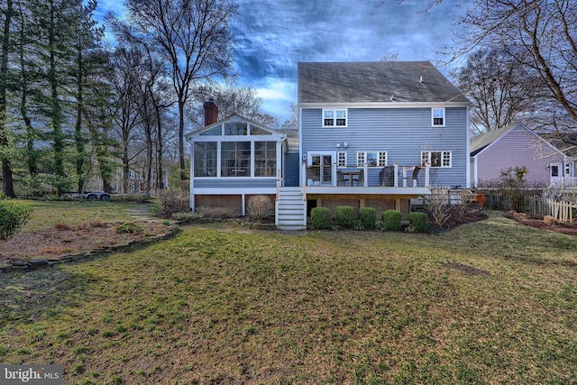 rear view of property with fence, a lawn, a chimney, a deck, and a sunroom