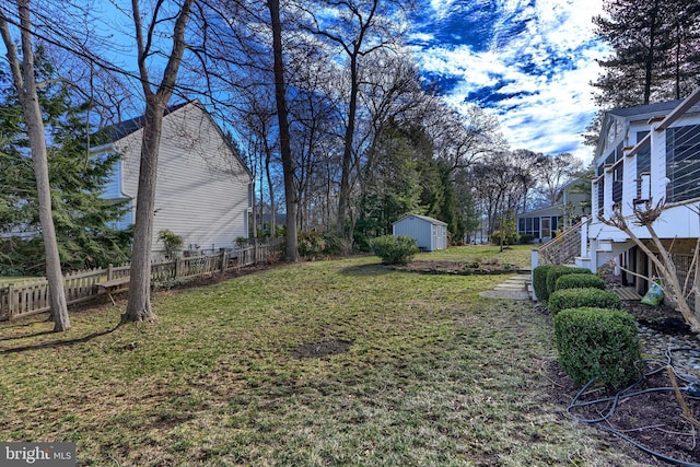 view of yard with fence, an outdoor structure, stairs, and a shed