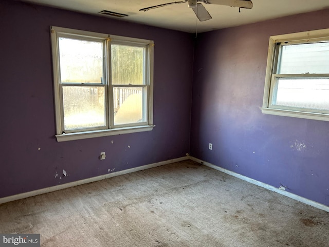 carpeted spare room with baseboards, visible vents, and a ceiling fan