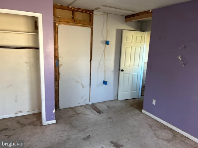 unfurnished bedroom with concrete floors and baseboards