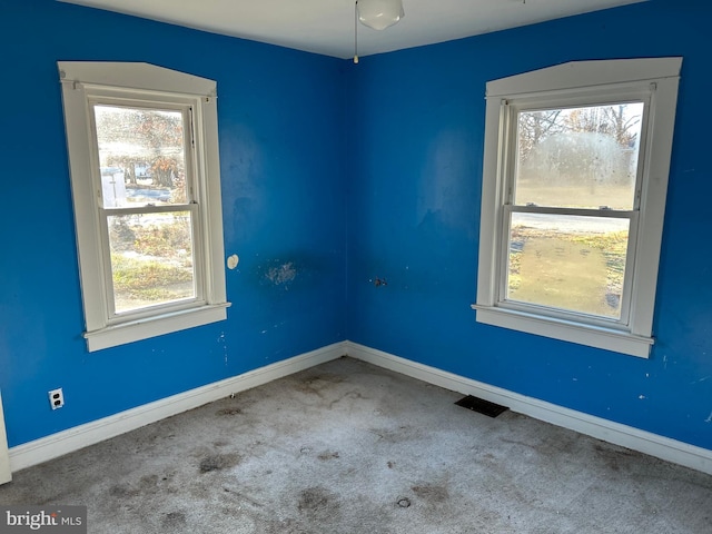 unfurnished room featuring carpet floors, visible vents, and baseboards