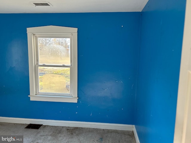 empty room with carpet flooring, visible vents, and baseboards