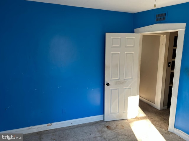 unfurnished room with carpet, visible vents, and baseboards