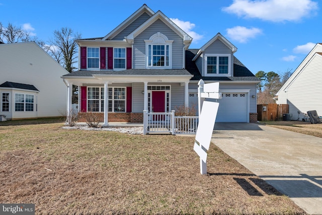 traditional-style house with brick siding, a front lawn, fence, a porch, and driveway