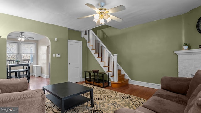 living area with stairs, wood finished floors, arched walkways, and baseboards