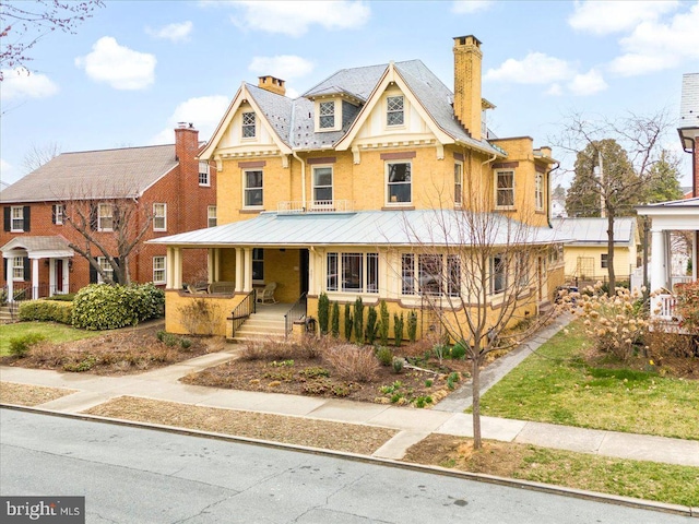 view of front of house featuring stucco siding, covered porch, and a chimney