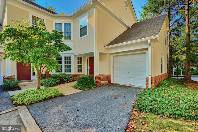 view of front of home featuring a garage, stucco siding, driveway, and brick siding