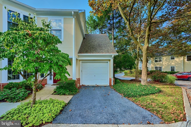 view of front of house with aphalt driveway, an attached garage, brick siding, roof with shingles, and stucco siding