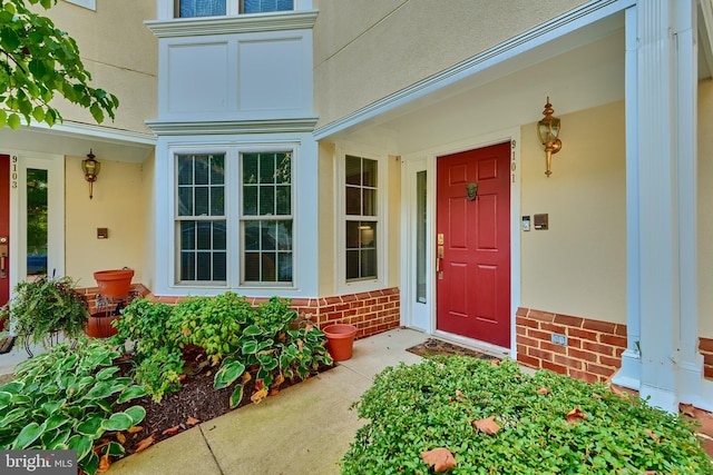 entrance to property featuring brick siding and stucco siding