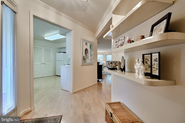 hallway with baseboards, light wood finished floors, and crown molding