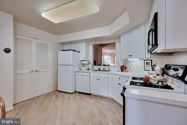 kitchen featuring white appliances, a sink, white cabinetry, light countertops, and light wood finished floors