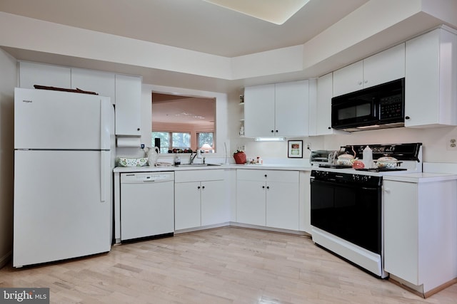 kitchen with white appliances, light countertops, a sink, and white cabinets