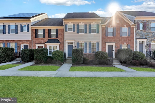 townhome / multi-family property with brick siding and a front yard