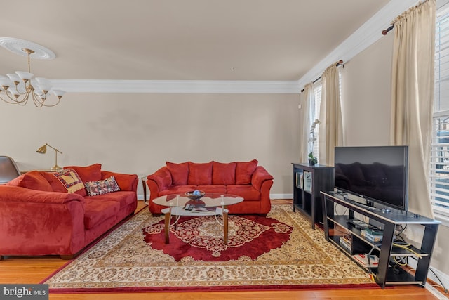 living area featuring crown molding, a notable chandelier, baseboards, and wood finished floors