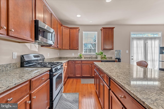 kitchen with plenty of natural light, light stone counters, stainless steel appliances, and light wood-style flooring