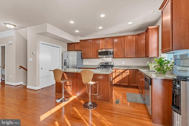 kitchen with a breakfast bar area, a center island, stainless steel appliances, light wood-type flooring, and recessed lighting