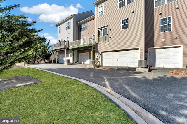 exterior space with a garage, driveway, central AC unit, and a front yard