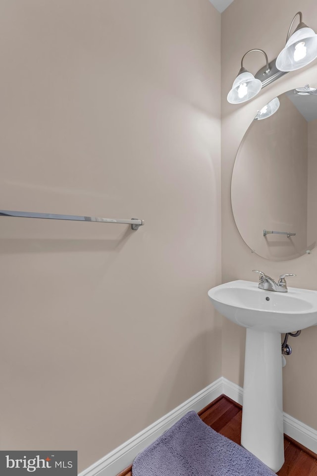 bathroom featuring a sink, baseboards, and wood finished floors