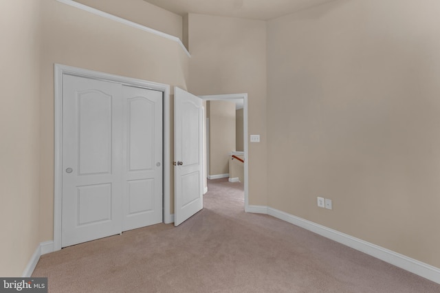 unfurnished bedroom featuring light carpet, a closet, and baseboards