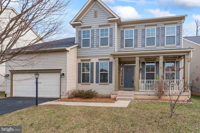 view of front of home featuring driveway, covered porch, an attached garage, and a front yard