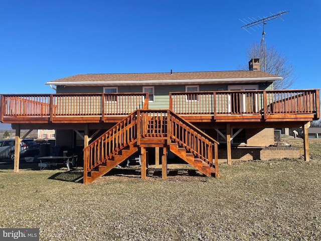 rear view of property with brick siding, stairway, a chimney, and a deck