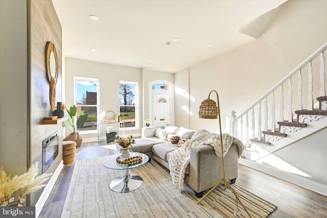 living area with baseboards, stairway, wood finished floors, a fireplace, and recessed lighting