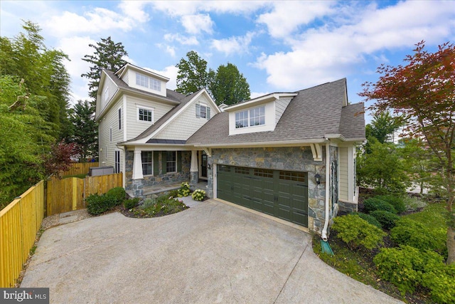 view of front of home with stone siding, fence, roof with shingles, concrete driveway, and an attached garage