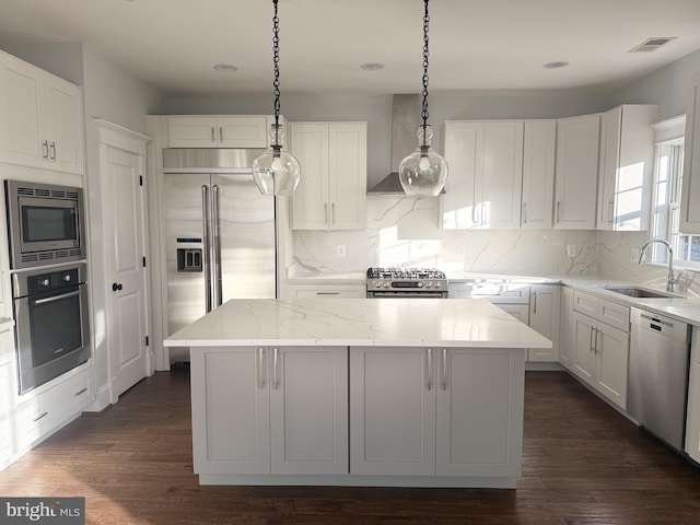 kitchen featuring visible vents, a kitchen island, dark wood-type flooring, built in appliances, and a sink