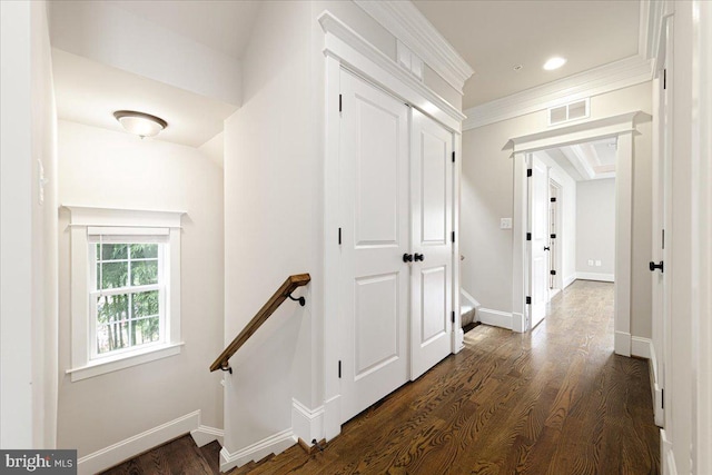 corridor featuring dark wood-style floors, visible vents, baseboards, crown molding, and an upstairs landing