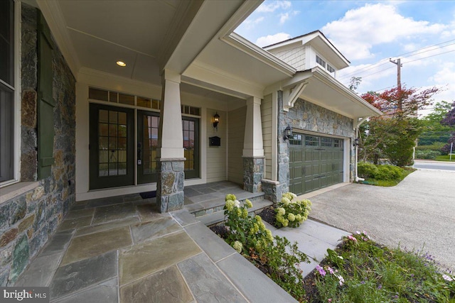 property entrance with covered porch, stone siding, and driveway