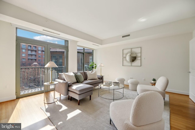 living room with baseboards, visible vents, and wood finished floors