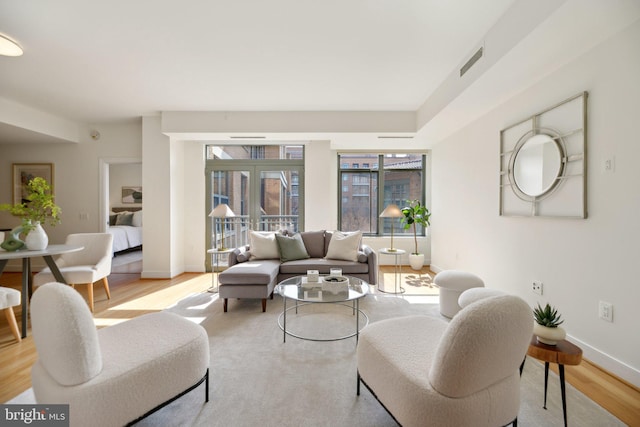 living area featuring light wood finished floors, visible vents, and baseboards