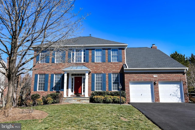 view of front of property featuring aphalt driveway, an attached garage, brick siding, and a front yard