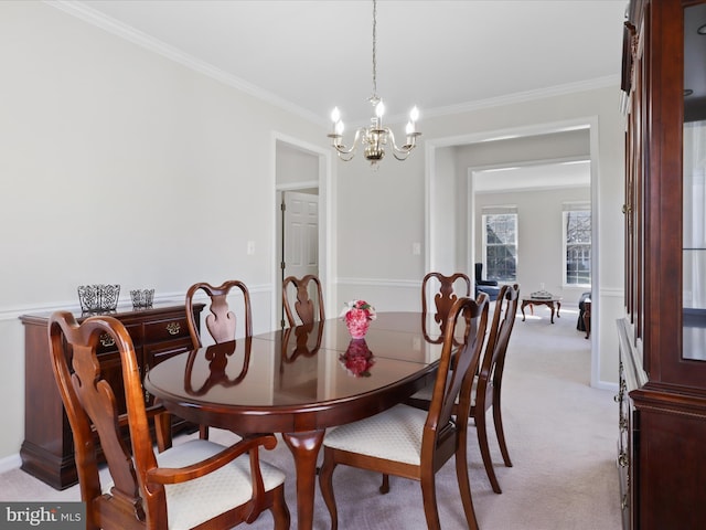 dining room with a chandelier, baseboards, light colored carpet, and ornamental molding