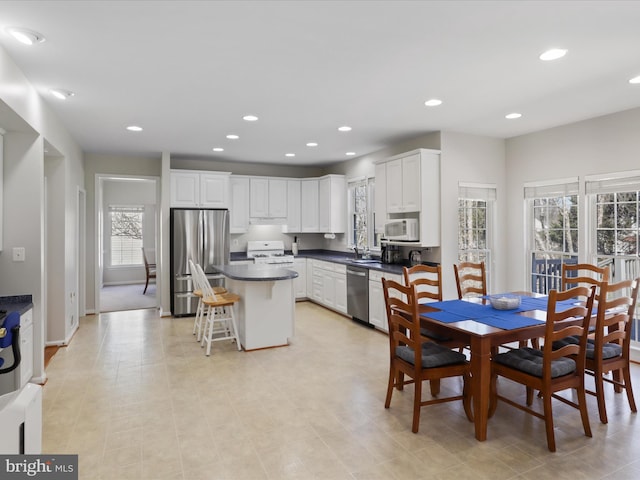 kitchen with recessed lighting, stainless steel appliances, dark countertops, and white cabinets