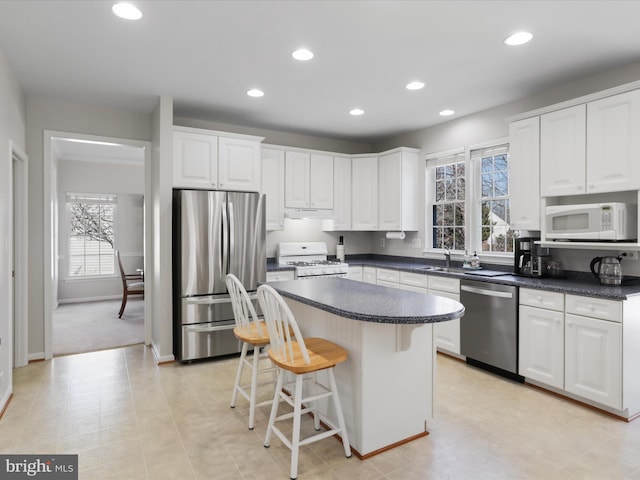 kitchen with stainless steel appliances, a kitchen breakfast bar, a kitchen island, and white cabinetry