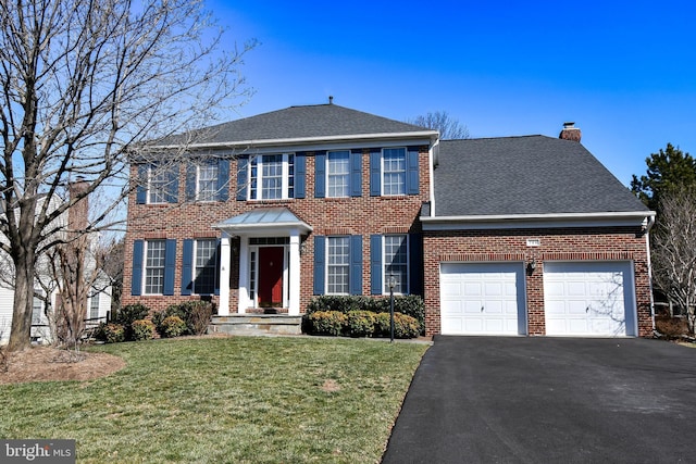 view of front of property featuring a front lawn, driveway, a garage, brick siding, and a chimney