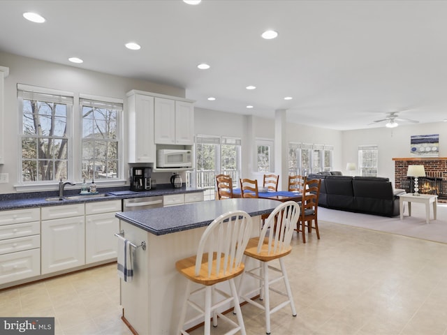 kitchen with a kitchen bar, a sink, a kitchen island, recessed lighting, and white microwave