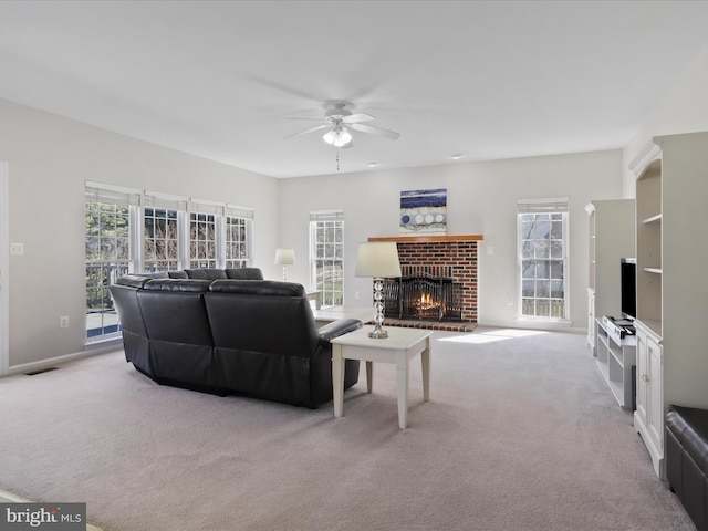 living area featuring visible vents, a healthy amount of sunlight, a brick fireplace, and a ceiling fan