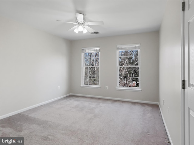 carpeted spare room with a ceiling fan, baseboards, and visible vents