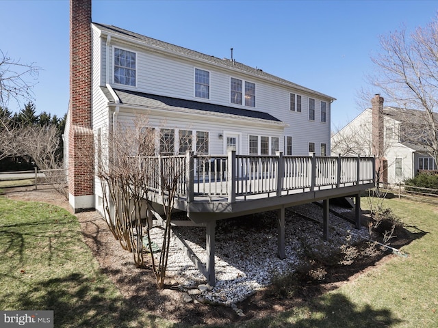 rear view of property with a wooden deck, a yard, fence, and a chimney