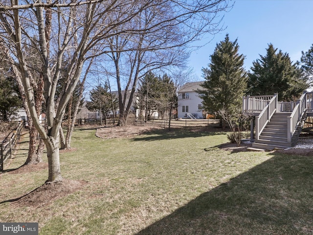 view of yard with a deck, stairs, and fence