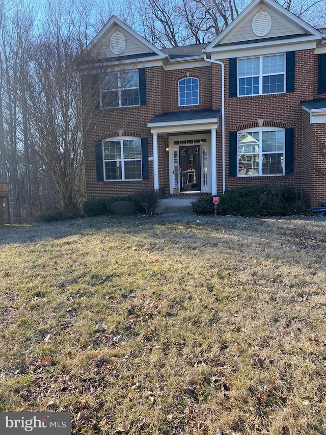 view of front facade with brick siding and a front yard