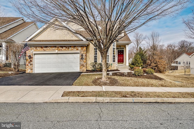 view of front facade with aphalt driveway, stone siding, an attached garage, and stucco siding