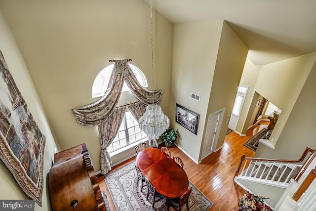 interior space with baseboards, a high ceiling, visible vents, and wood finished floors