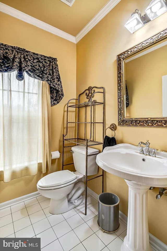 half bathroom with baseboards, tile patterned flooring, toilet, and crown molding