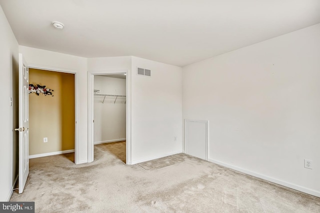 unfurnished bedroom with carpet floors, a closet, visible vents, and a spacious closet